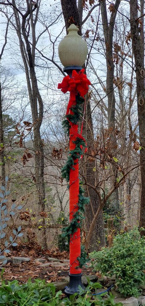 a street light decorated for christmas with red ribbon and bows on it's ...