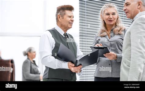 Close Up Group Of Employees Discussing Documents Standing In The