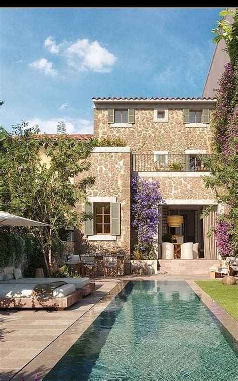 An Outdoor Swimming Pool In Front Of A House With Trees And Flowers On