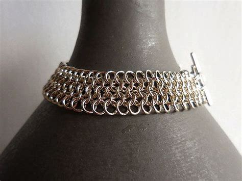 a silver chain bracelet sitting on top of a gray mannequins neckpiece