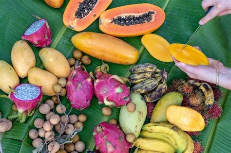 Surtido de frutas tropicales en hojas de plátano verde y manos de