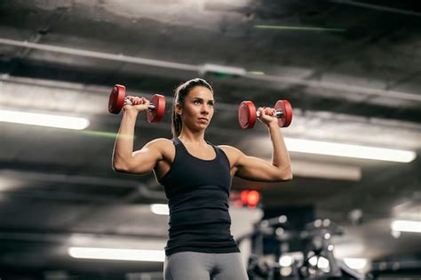 Una deportista musculosa fuerte está levantando pesas en un gimnasio