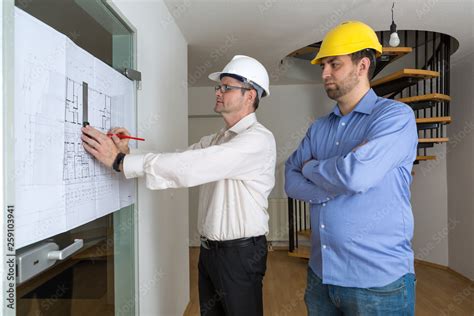 Architekt mit weißem Helm zeichnet den Wunsch des Bauherren mit gelbem