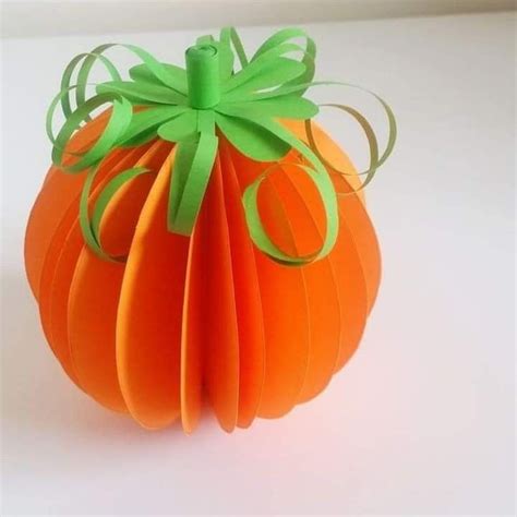 An Origami Pumpkin Sitting On Top Of A White Table Next To A Green Ribbon