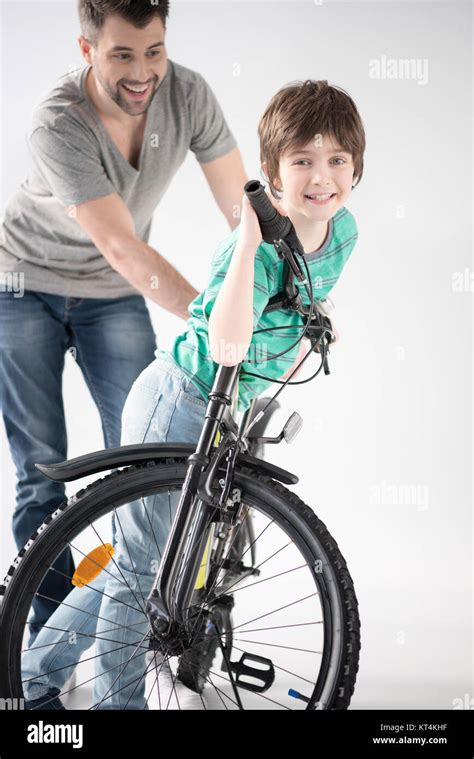 Cheerful Father Teaching Son How To Ride Bicycle On White Stock Photo