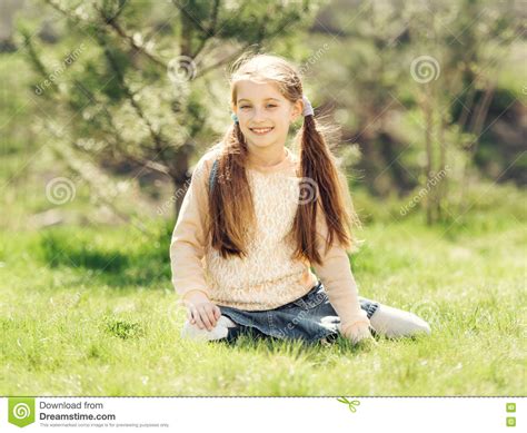 Petite Fille De Sourire Mignonne S Asseyant Sur L Herbe Photo Stock