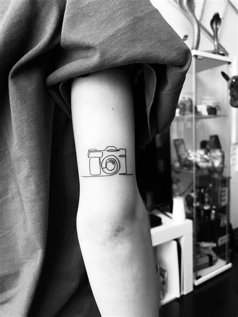 A Camera Tattoo On The Left Arm And Wrist Is Shown In This Black And