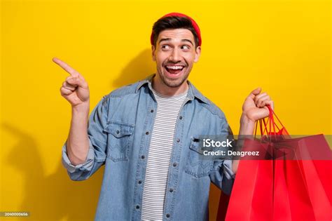 Photo Of Impressed Positive Man Dressed Jeans Shirt Holding Shoppers Showing Empty Space