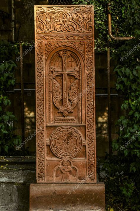 Una toba roja khachkar con un patrón floral sobre un arco con una cruz