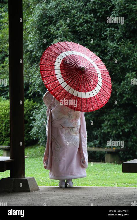 Back View Of A Japanese Woman Wearing A Kimono And Carrying A Paper