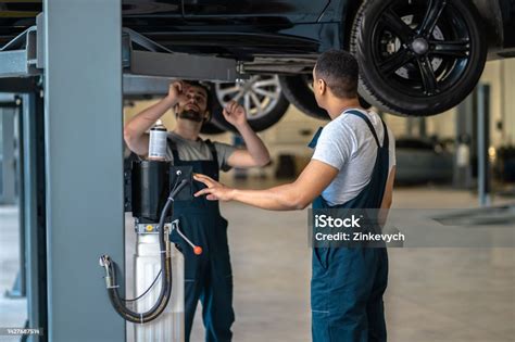 Two Professional Mechanics Performing Visual Inspection Of The Vehicle