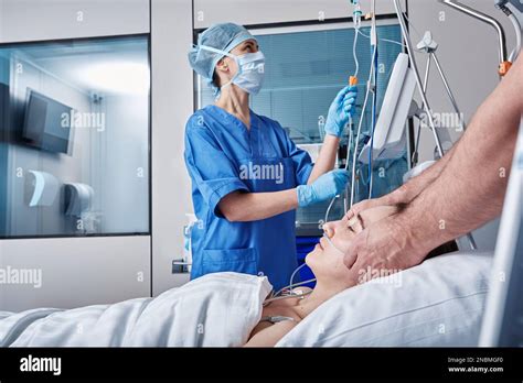 Two Doctors Checking On Unconscious Woman Patient At Intensive Care