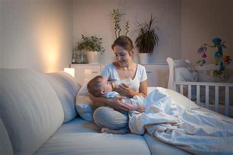 Mother Giving Milk To Her Baby In Bed At Night Stock Photo Download