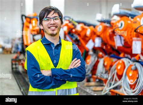 Proud Japanese Chief Engineer Of A Robotic Industry Standing With Arms