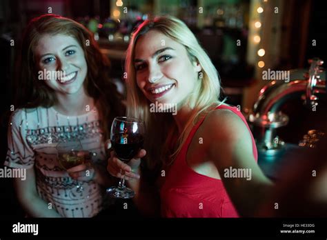 Friends Taking Selfie From Mobile Phone While Having Wine At Counter In