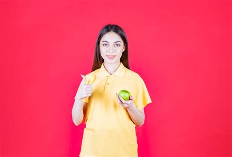 Free Photo Young Woman In Yellow Shirt Holding A Green Apple And