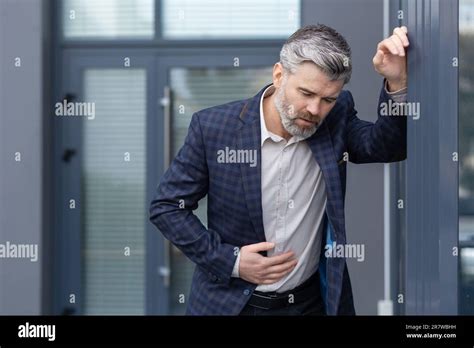 Mature Gray Haired Boss Has Food Poisoning Man Outside Office Building