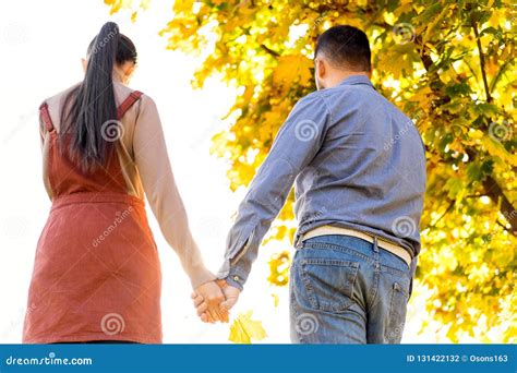 Young Couple In Love Walking In The Autumn Park Holding Hands Looking