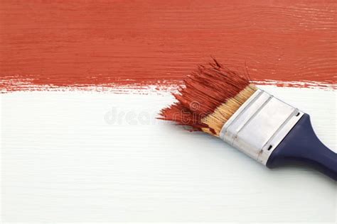 Paintbrush With Red Paint Painting Over White Board Stock Photo