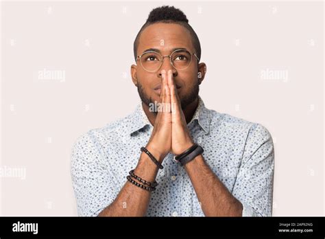 Hopeful Black Man Isolated In Studio Join Hands In Prayer Stock Photo
