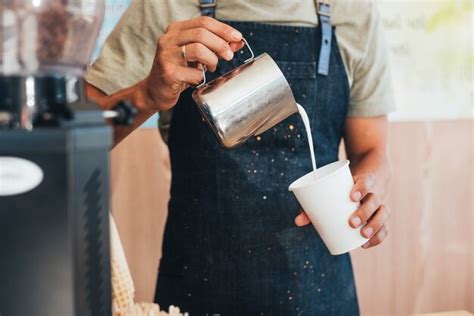 Premium Photo The Barista Pours Milk From A Tin Can Into Coffee In A