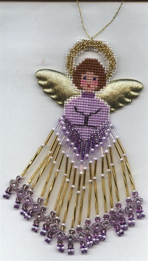 A Cross Stitch Angel Ornament With Purple Beads And Gold Chains On A