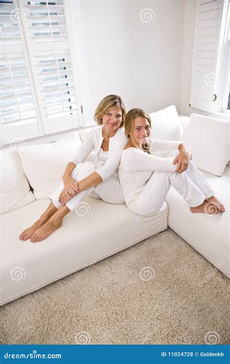 Mother And Teenage Daughter Relaxing On White Sofa Royalty Free Stock