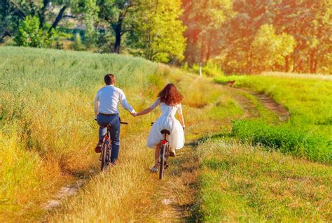 Premium Photo Young Happy Bride And Groom Ride Bicycles In The Meadow