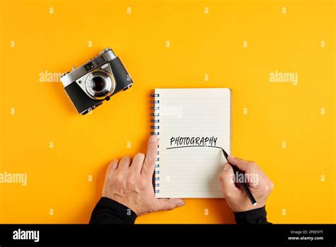 Male hand writing the word photography in a notebook next to an old ... 