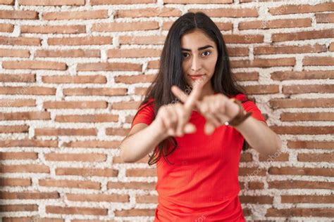 Joven Adolescente Chica De Pie Sobre Ladrillos Pared Rechazo Expresión Cruzando Dedos Haciendo