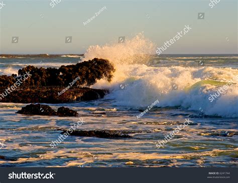 Waves Crashing Against The Rocks At Sunset Stock Photo