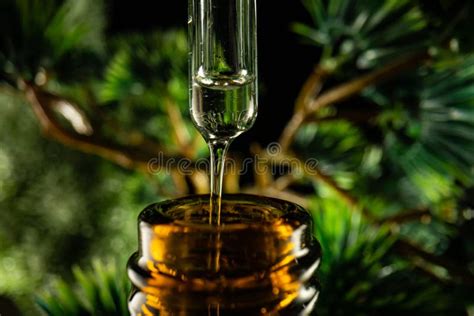 Essential Oil Dripping From Pipette Into Glass Bottle On A Blurred