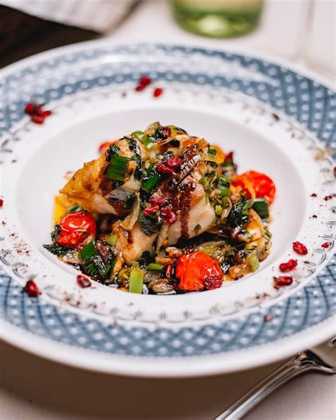 Vue latérale du filet de poisson frit aux herbes et légumes en sauce