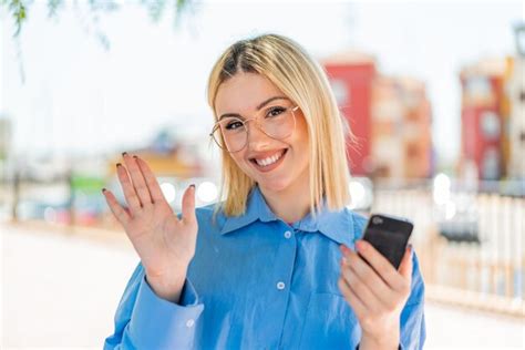 Junge hübsche blonde frau im freien mit dem handgerät telefoniert und mit einem glücklichen