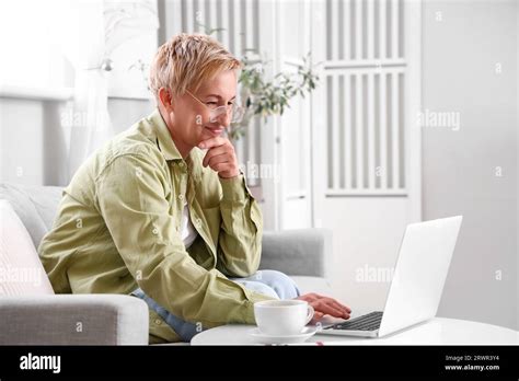 Mature Female Programmer Working With Laptop On Sofa At Home Stock