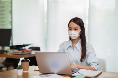 Premium Photo Businesswoman Wearing Mask Using Laptop While Sitting