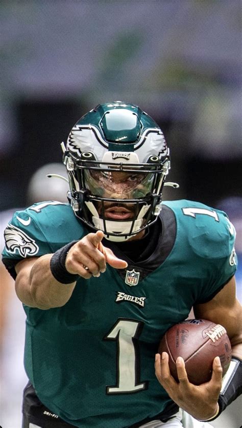 A Man Holding A Football In His Right Hand And Wearing A Helmet With