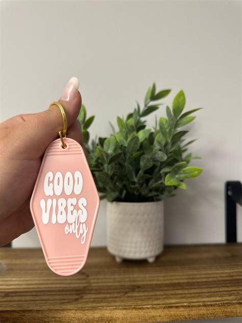 A Hand Holding A Pink Keychain That Says Good Vibes Only