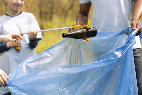 Diverse activists collecting garbage and plastic from the forest