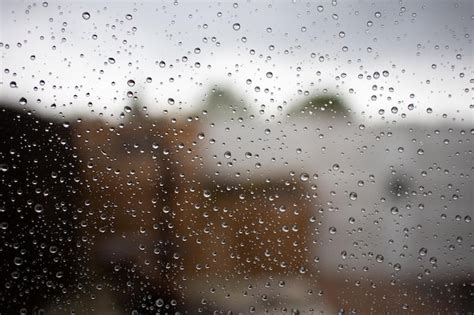 Gotas De Lluvia En Una Ventana Con Una Casa Al Fondo Foto Premium