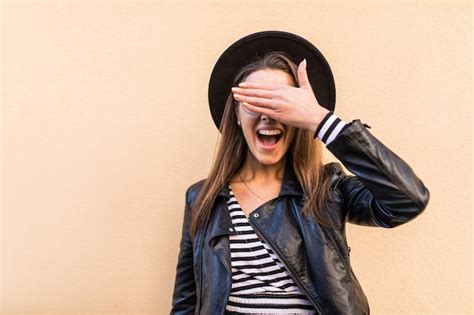 Belle fille de mode en veste de cuir et chapeau noir couvrir son œil de