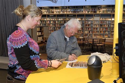 Two People Are Sitting At A Table In The Library