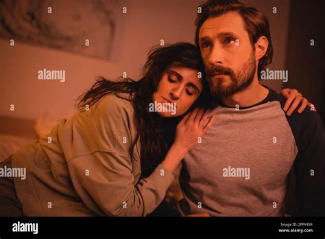 Brunette Woman Hugging Sad Boyfriend In Bedroom At Nightstock Image