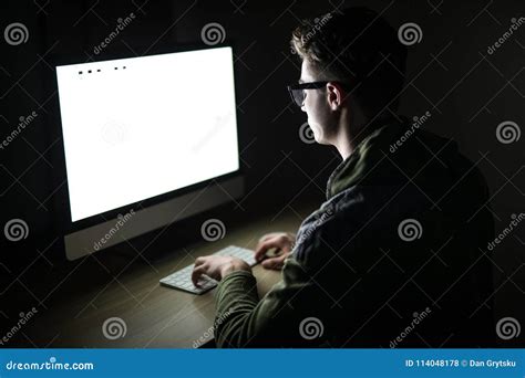 Closeup Of Young Man Sitting And Using Blank Screen Computer In Dark