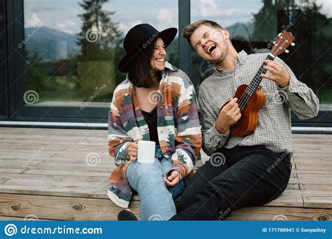 Hipster Man Playing On Ukulele For His Stylish Woman Relaxing On