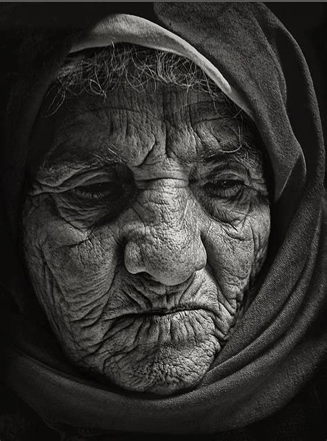 An Old Woman Wearing A Headscarf And Looking At The Camera With Her