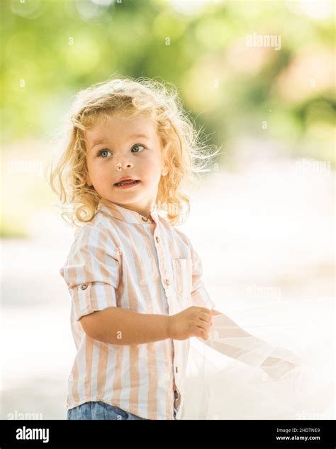 Cute little boy with curly blonde hair playing in park Stock Photo - Alamy