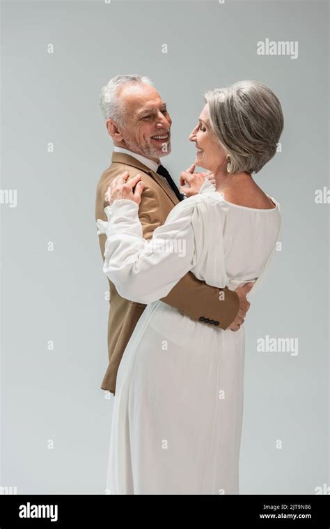 Happy And Mature Groom And Bride In Wedding Dress Dancing Isolated On