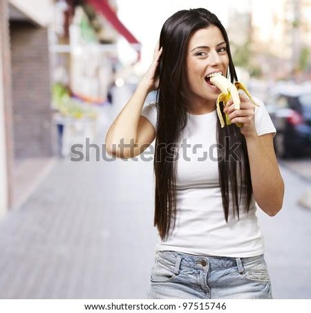 young woman eating a banana against a street background - stock photo