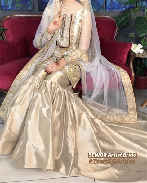 A Woman Sitting On Top Of A Red Couch Wearing A Dress And Headpieces